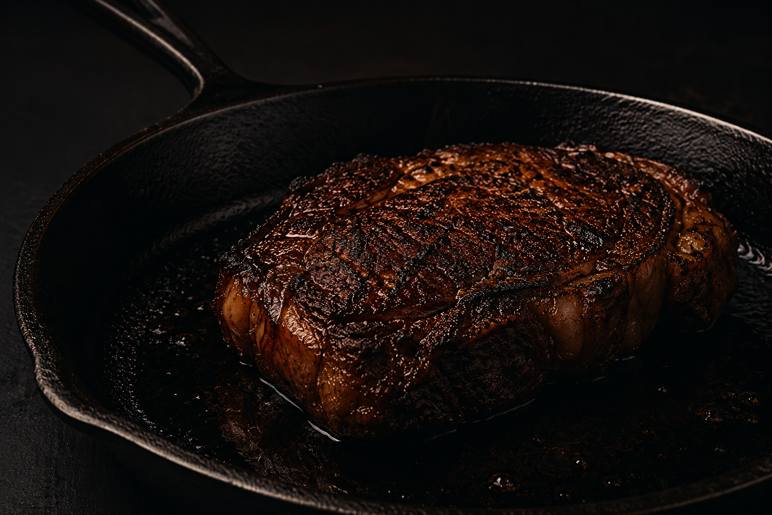 A seared ribeye resting in a cast-iron skillet